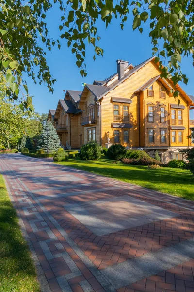 Un hermoso paisaje de día de verano en un parque con un césped verde y un camino cercano y una magnífica casa de arquitectura elegante con un árbol envainado . — Foto de Stock