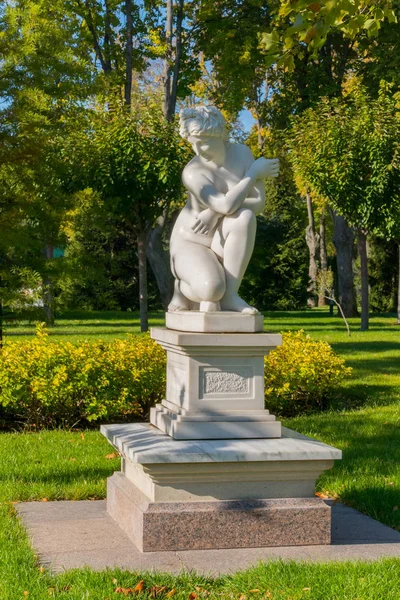 Vackra gips skulptur av en sittande kvinna i en park på en matta av grönt gräs — Stockfoto