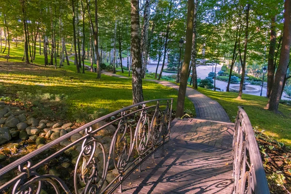 Un petit pont à travers le lac menant à un bâtiment moderne au loin — Photo