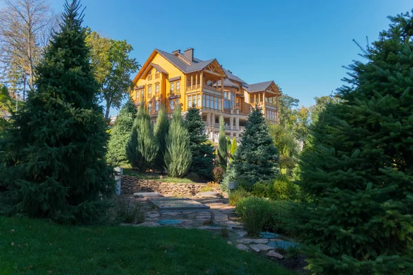 uxurious green and blue fir in the park on the background of a house on top of a hillock