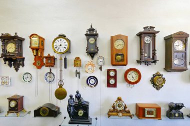 Müzeler tesislerinde beyaz bir duvar çeşitli şekil ve büyüklükte antika saatler topluluğu yerleştirilen.