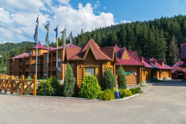 Bir bayrak direğine ve üzerinde uçan bayraklar ile güzel mimari evler ile karmaşık bir otel. Yüksek çam ağaçları ile yeşil ormanın yanında ayakta.