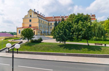 Banklar yemyeşil ağaçlar ve bulutlu bir gökyüzü karşı yeşil çim yeşil bir alanda bir tarihi bina konumu olan şehir manzarası.