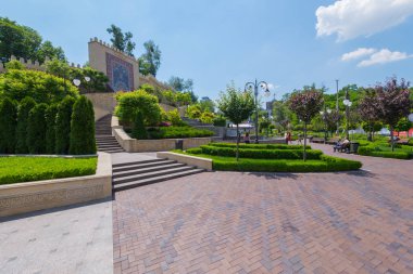 Güzel park geniş yolları banklar sulu yeşil çimenler ve yüksek bir duvar ile dinlenme için süsler ile dekore edilmiştir.