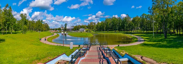 Ένα υπέροχο πανόραμα του μια ηλιόλουστη μέρα του καλοκαιριού σε ένα πάρκο με μια λιμνούλα και ένα καταπράσινο νησί στη μέση και λευκά σύννεφα αιωρούνται πάνω από αυτή την ομορφιά — Φωτογραφία Αρχείου