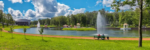 Céu transparente claro ligeiramente apertado por nuvens no fundo de pessoas que descansam em um banco pela lagoa — Fotografia de Stock