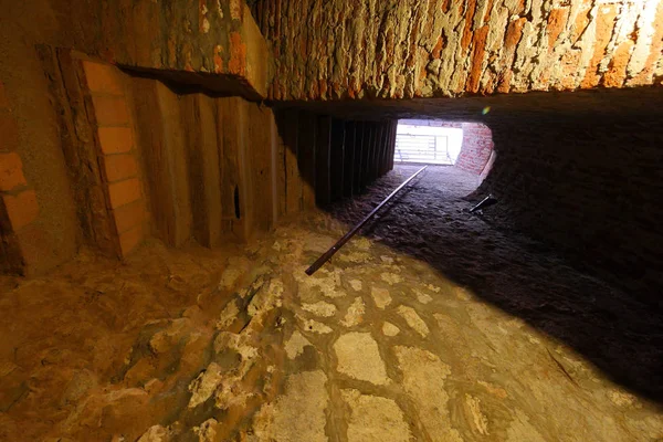 Túnel en la pared con un paso de techo bajo a lo largo del cual solo se puede doblar hacia abajo. Lleva hacia adelante a un punto de luz blanca . . — Foto de Stock