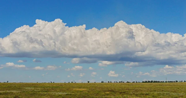 A white cloud hanging over the far horizon of the green plain hat — Stock Photo, Image