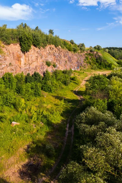 En vacker vy från ovan på grusvägen mellan skogen och en ren stenig kulle — Stockfoto