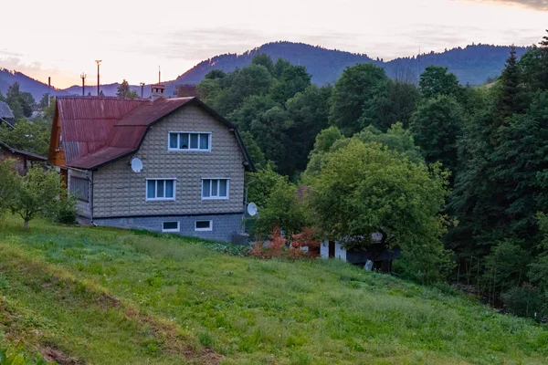 Trzy piętrowy dom przed lasem i góry — Zdjęcie stockowe