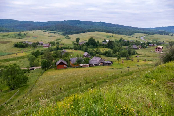Kleine Bauernhäuser mit Höfen vor dem Hintergrund weiter grüner Bergketten — Stockfoto