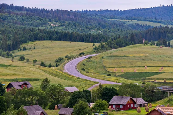 Karpatendorf in der Nähe der Straße im Hintergrund des Waldes — Stockfoto