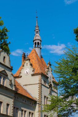 Çatıda bir sivri sivri ile yüksek bir kule iki tarafında saat yüzü ile güzel mimari ile eski bir ev.