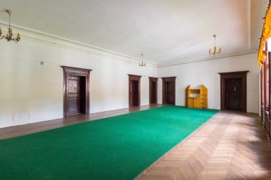 Beyaz duvar ve tavan ve parke üzerinde asılı avizeler ile birçok kapı büyük geniş koridor yerde.