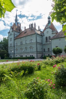 Kahverengi bir çatı ve kuleleri ile eski, taş castle. Civarında bahçenizi güzel çiçeklerle vardır
