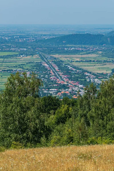 Una vista encantadora de la colina a la ciudad que miente en un valle de la montaña con una calle central y techos de casas entre la vegetación a cada lado de ella . —  Fotos de Stock