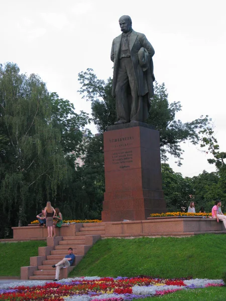 Un monumento a un poeta nacional en un parque entre hermosas flores con gente descansando a sus pies — Foto de Stock