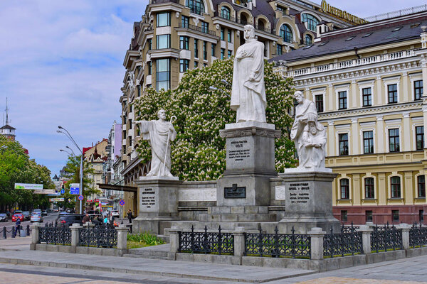 Скульптуры, посвященные известным историческим деятелям на фоне высоких современных зданий
