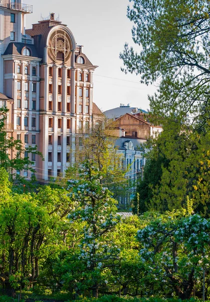 Moderna hermosa casa de varios pisos contra el fondo de árboles con flores verdes y el cielo azul — Foto de Stock