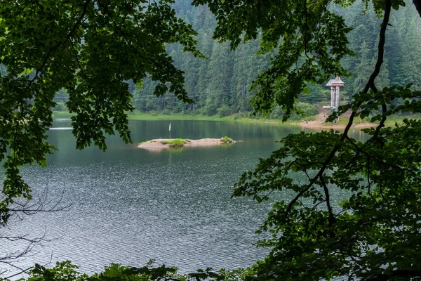 Uma pequena ilhota arenosa com uma bandeira no meio de um lago azul transparente — Fotografia de Stock