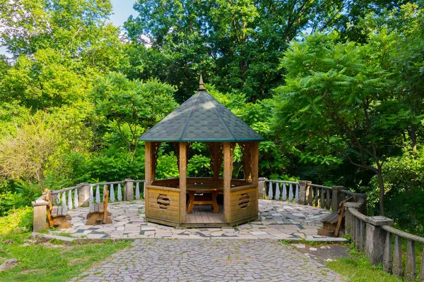 Una pintoresca zona de recreo con una pérgola de madera con techo verde y bancos a los lados . —  Fotos de Stock