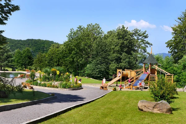 O beco do parque que conduz a um canteiro de flores redondo decorativo e a um grande parque infantil — Fotografia de Stock