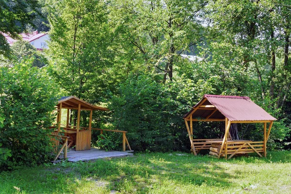 Ein Ruheplatz mit Bänken und einem Tisch, der im Schatten von Büschen und Bäumen auf dem grünen Rasen steht. ein guter Ort zum Entspannen in Ruhe und Einsamkeit. — Stockfoto