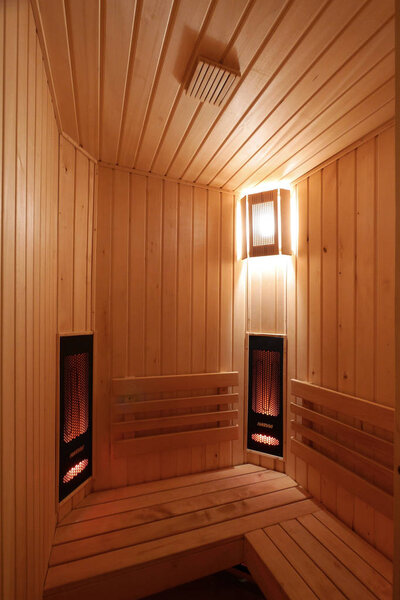a room in a sauna lined with wood with a soft light of a wall lamp