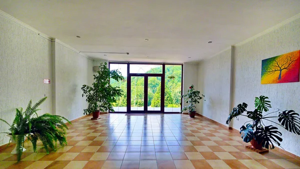 Просторий зал з балконом, різнокольоровою плиткою на підлозі та декоративними рослинами — стокове фото