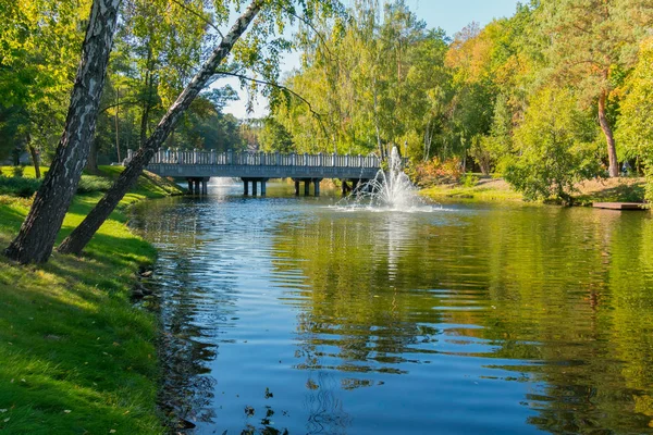 River with a fountain and a bridge and with birches on the shore — Stock Photo, Image