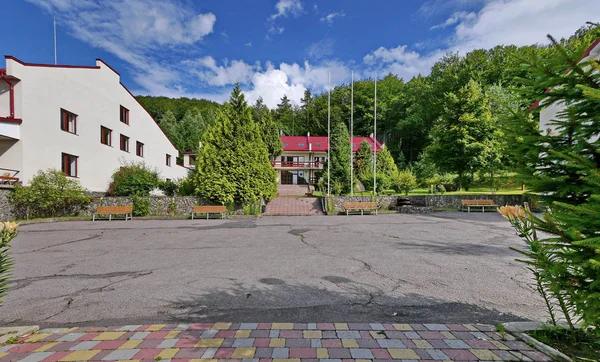 Parque infantil de asfalto con bancos para descansar en el fondo de una casa de hotel y un bosque verde — Foto de Stock