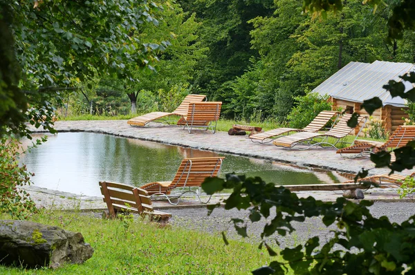 Ein malerisches Schwimmbad mit hölzernen Liegestühlen an den Seiten im Hintergrund eines grünen Waldes — Stockfoto