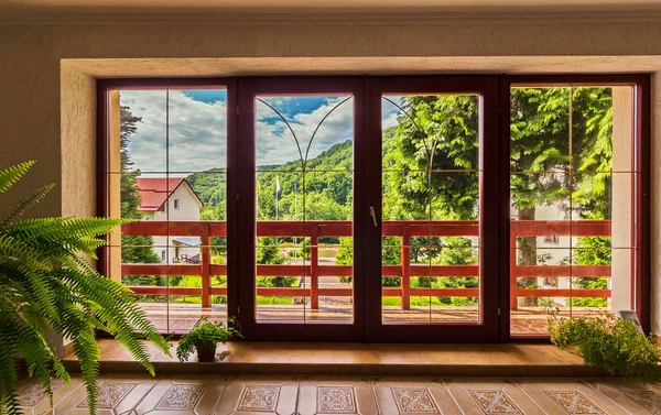 Grandi porte di vetro nella casa su cui si apre un panorama di montagne sotto il cielo blu — Foto Stock