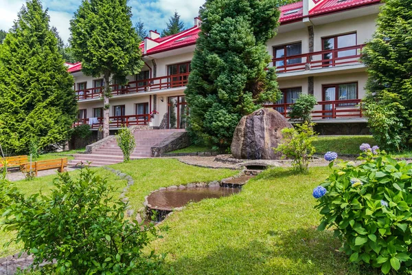 Fuente decorativa, escalones con bancos y un moderno edificio de un complejo hotelero con techo rojo sobre un fondo de árboles verdes — Foto de Stock