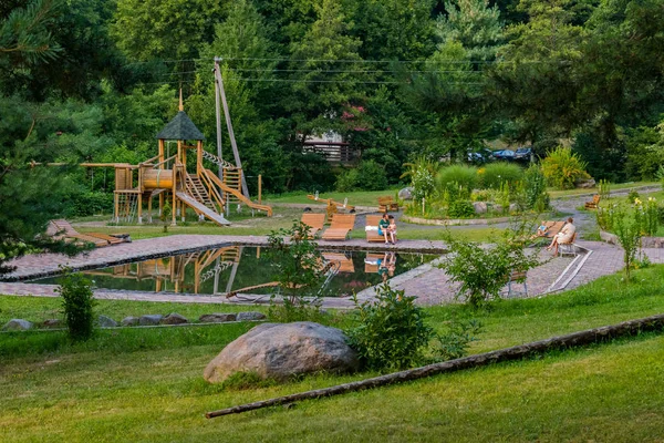 Vater mit Kind auf einer Bank in einem Park mit einer Spielfläche aus Holzbalken — Stockfoto