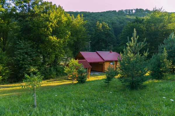 Ein Pavillon in der Nähe eines Holzhauses mit rotem Dach auf der Waldlichtung — Stockfoto