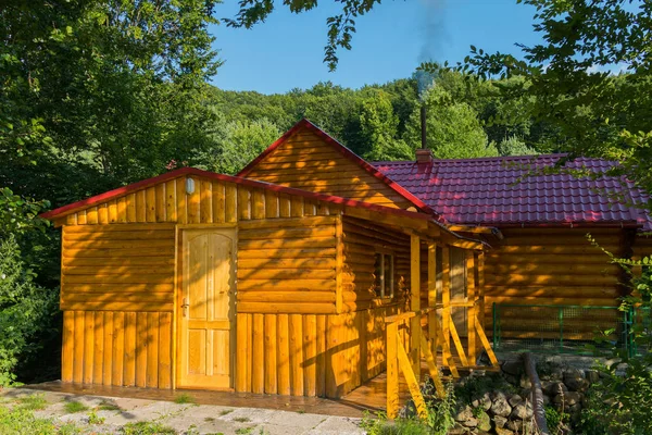 Casa de baño forrada de madera con una pipa humeante en el fondo de un bosque verde —  Fotos de Stock