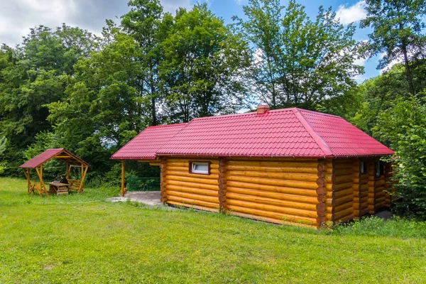 Dům se skládá z dřevěného rámu s malými okny a červenou střechou, se nachází poblíž altánu — Stock fotografie
