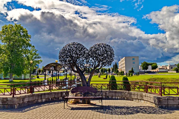 Composição de uma árvore de ferro na forma de duas bolas e bancos no parque contra um belo céu — Fotografia de Stock