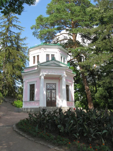 Bâtiment rose en forme de diamant avec un toit vert sur le fond des épicéas — Photo