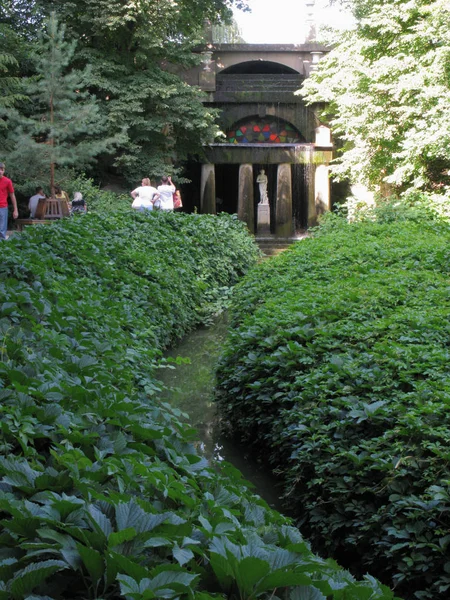 Ein kleiner Flussgraben, der zur Skulptur einer Frau auf dem Hintergrund eines Gebäudes mit riesigen Säulen führt — Stockfoto