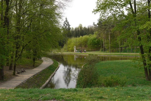 Řeka nedaleko uličky s dřevěnými lavicemi pro relaxaci v zeleném parku — Stock fotografie