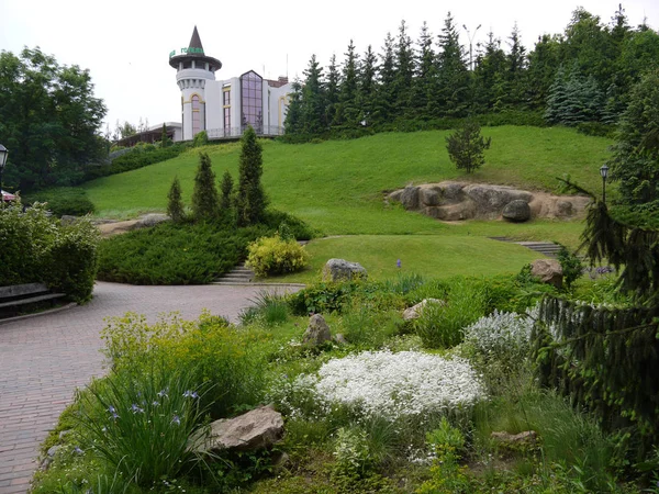 O palácio com um belo gramado verde ao redor, com grandes pedras, arbustos, árvores e um canteiro de flores — Fotografia de Stock
