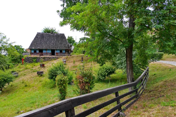 Una pequeña casa privada en una pendiente con hierba verde está cercada por una cerca de madera, simple —  Fotos de Stock