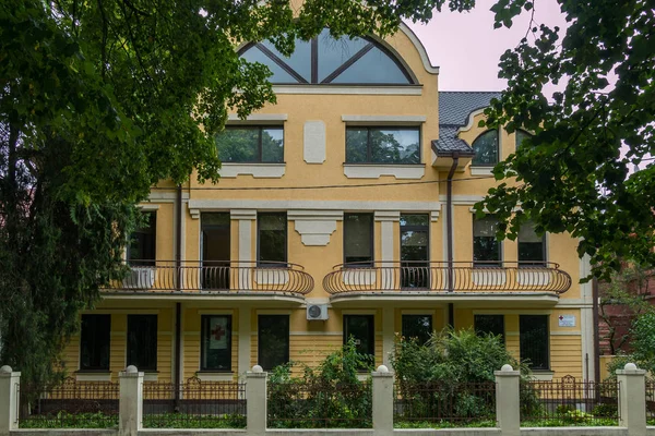 Ein schöner Blick auf die Fassade des Gebäudes mit Balkonen, die hinter einem niedrigen Zaun mit wachsenden grünen Büschen stehen. — Stockfoto