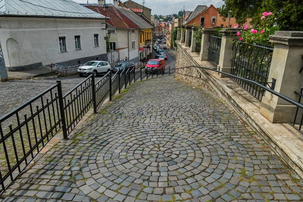 Uma estrada de paralelepípedos atrás de uma cerca preta em uma pequena cidade — Fotografia de Stock