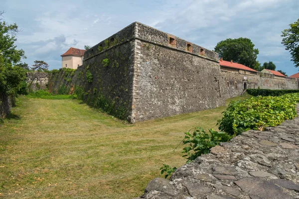 Parede de fortificação de pedra alta com janelas contra um fundo de gramado verde — Fotografia de Stock
