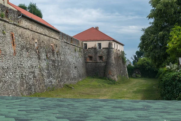 Красивый дом с красной крышей, скрытой у стен старой крепости — стоковое фото