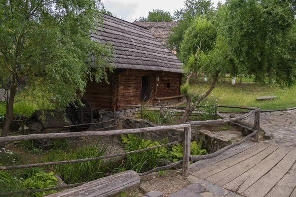 Ponte de madeira no fundo de um moinho de água e uma casa de madeira — Fotografia de Stock