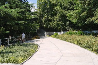 Bir rahat park alanındaki her tarafında çiçek yatak ile bir geniş yürüyüş sokak